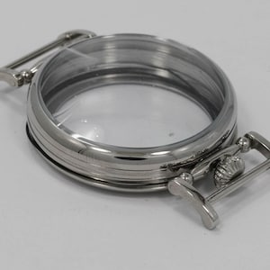 May include: A silver watch case with a clear glass face and a hinged clasp.
