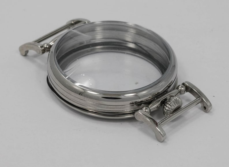 May include: A silver watch case with a clear glass face and a hinged clasp.