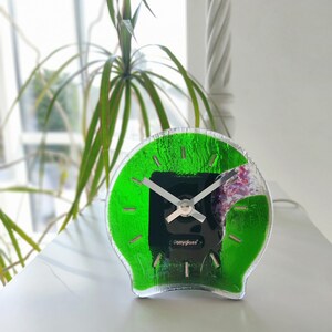 Könnte beinhalten: Eine grüne Glasuhr mit silbernen Zeigern und einem schwarzen Zifferblatt. Das Zifferblatt der Uhr trägt den Text "Ponyglass".