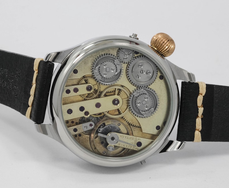 May include: A silver pocket watch with a skeletonized dial, revealing the intricate inner workings of the movement. The watch has a black leather strap with white stitching and a gold-toned crown.