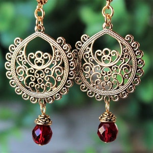 May include: Gold filigree earrings with dangling red crystal beads.