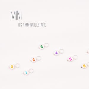 Könnte beinhalten: Weiße Kunststoff-Maschenmarkierer mit bunten Zahlen von 0 bis 6. Der Text "MINI BIS 4 MM NADELSTÄRKE" ist oben im Bild sichtbar.