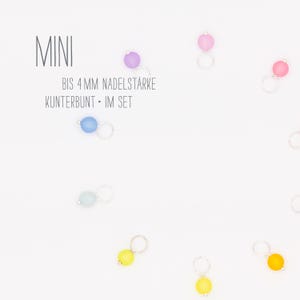 Könnte beinhalten: Ein Set bunter Maschenmarkierer zum Stricken oder Häkeln. Die Markierer sind aus Glas und haben einen Metallring. Der Text auf dem Bild lautet "MINI BIS 4 MM NADELSTÄRKE KUNTTERBUNT - IM SET".