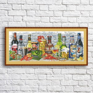 May include: A framed cross-stitch artwork depicting a variety of beer bottles, cans, and glasses. The bottles include brands like 'Vampire', '184', 'Lays', 'Heineken', 'Redd's', '1664 Blanc', and 'Argobla'. The artwork also features a glass of wine, a bowl of peanuts, and a few crawfish.