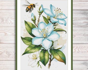 Könnte beinhalten: Gerahmtes Kreuzstich-Design mit hellblauen Blumen, grünen Blättern und einer Biene. Das Kunstwerk hat einen Aquarell-Effekt auf weißem Hintergrund, ist grün gerahmt und vor einem Holzmaserungshintergrund angebracht. Größe ca. 30 cm x 40 cm.
