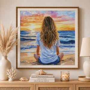 Peut inclure: Une peinture à l'aquarelle carrée encadrée représentant une personne aux longs cheveux ondulés assise sur une plage de sable face à l'océan au coucher du soleil. Le ciel est rempli de teintes orange, rose et jaune, avec des vagues bleu foncé.