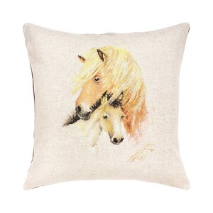 Puede incluir: Una almohada beige con un caballo y un potro de color crema bordados en ella. El caballo está mirando hacia la izquierda y el potro está acurrucado contra el cuello del caballo. El caballo tiene una crin y una cola de color marrón claro.