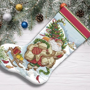 May include: A white Christmas stocking with a red and white striped cuff. The stocking features a Santa Claus carrying a Christmas tree and presents on a sled. The stocking is decorated with green holly and red berries.