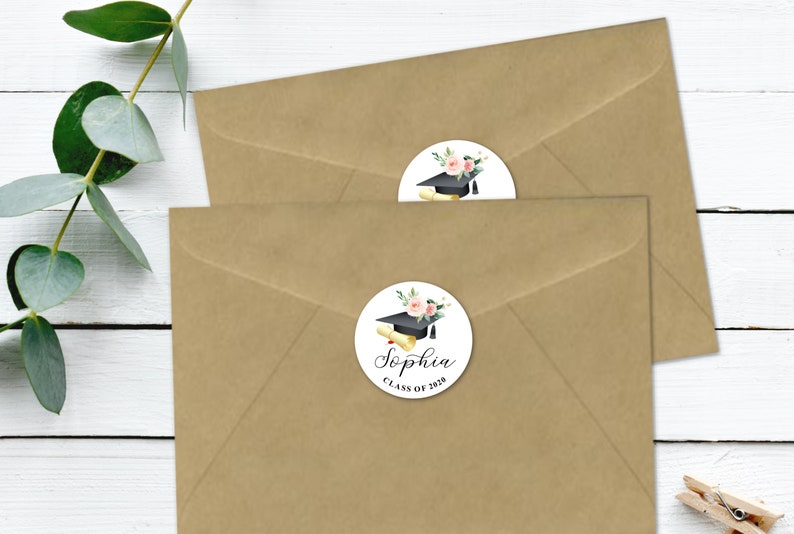 May include: Two brown envelopes with round white graduation stickers. The stickers feature a black graduation cap, a diploma, pink flowers, and green leaves. The text on the sticker reads "Sophia Class of 2020".
