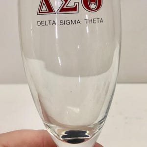 Puede incluir: Una taza de cer&aacute;mica blanca con un asa negra y el texto "But First, Coffee" en negro y negrita. La taza est&aacute; sobre una superficie blanca. La taza mide aproximadamente 10 cm de alto.