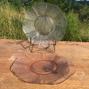 Puede incluir: Dos platos de vidrio vintage, uno es de color verde pálido con un diseño floral y el otro es de color rosa pálido con un diseño acanalado.