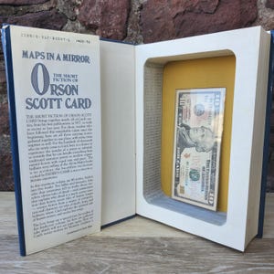 Caja fuerte con forma de libro. Mapas en un espejo. Cierre magnético. Tarjeta de Orson Scott. Relatos breves.