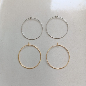 Peut inclure: Quatre boucles d'oreilles créoles, deux argentées et deux dorées, sur une surface blanche.