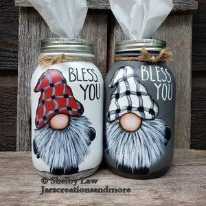 Peut inclure: Deux bocaux en verre décorés de gnomes et des mots "Bless You". Les bocaux sont peints en blanc et gris et ont un motif à carreaux sur les chapeaux de gnome. Les bocaux sont utilisés comme porte-mouchoirs.