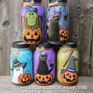May include: Five decorated glass jars with Halloween themes. Each jar has a different character painted on it, including a ghost, a witch, a black cat, Frankenstein, and a witch with a broom. Each jar also has a pumpkin with a jack-o-lantern face painted on it.
