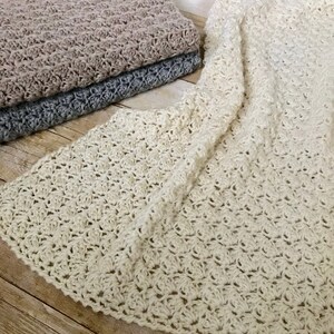 May include: Three crocheted blankets in different colors: beige, gray, and white. The blankets are made with a delicate stitch pattern and have a soft, textured feel.