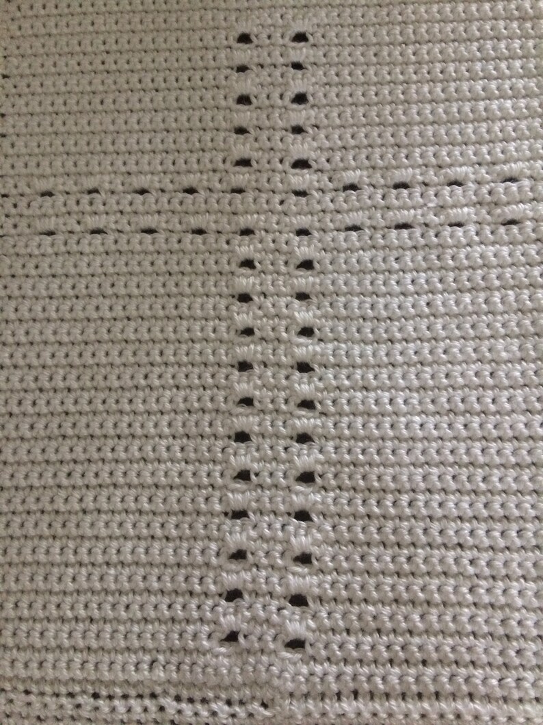 May include: A close-up of a white crocheted fabric with a repeating pattern of holes.
