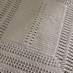 May include: White crocheted blanket with a diamond pattern.