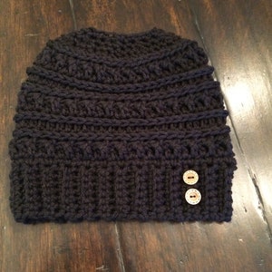 May include: A black crocheted beanie with two brown buttons.