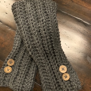 May include: A pair of gray crocheted fingerless gloves with wooden button accents.
