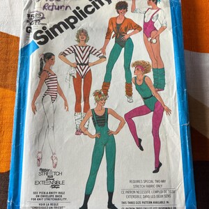 Peut inclure: Une pochette de patron de couture Simplicity, numéro 6485, présentant des illustrations de divers justaucorps, leggings et tenues de sport. La couverture affiche du texte incluant Simplicity, le numéro 6485 et des instructions sur les exigences en matière de tissu extensible dans les deux sens pour les vêtements présentés.