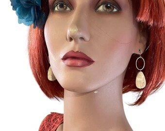 May include: A pair of dangle earrings with a light brown oval-shaped stone. The earrings are hanging from a silver hoop.