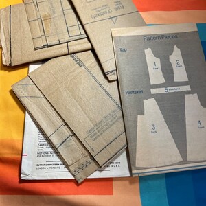 Puede incluir: Un conjunto de patrones de costura de papel marr&oacute;n para una blusa y una falda pantal&oacute;n. Las piezas del patr&oacute;n est&aacute;n etiquetadas con n&uacute;meros y nombres, incluyendo "Top", "Espalda", "Delantero", "Falda pantal&oacute;n", "Cintura". El patr&oacute;n es de la marca "Butterick" e incluye instrucciones para coser.