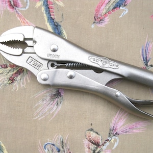 May include: A silver-colored metal locking plier tool featuring a curved jaw design. The tool is stamped with the text IRWIN, 7WR, and VISE-GRIP. It includes a tension adjustment screw at the end of the handle and a visible metal coil spring.