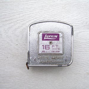 May include: A vintage Lufkin 16-foot metal measuring tape. The tape measure has a silver case with a purple and white label that reads "Lufkin" and "16 FT." It also includes the text "Add 2 1/4" for case" and "Add 2 inches for inside measure."
