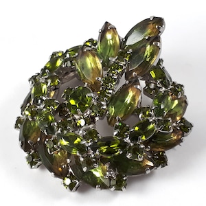 May include: A vintage brooch with a cluster of green and gold rhinestones in a floral design.