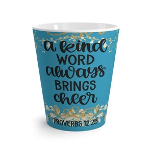 May include: A teal ceramic mug with the words "a kind word always brings cheer" in black script. The mug also features the Bible verse Proverbs 12:25. Gold and white floral accents decorate the top and bottom of the mug.