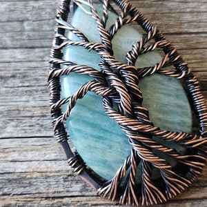 May include: A copper wire tree of life pendant with a light blue agate stone in the center.