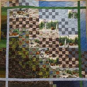 Puede incluir: Una colcha con un patrón a cuadros en tonos marrones y azules. La colcha está compuesta por cuadrados más pequeños, cada uno con una escena de naturaleza diferente, incluyendo árboles, animales y paisajes. La colcha está bordeada con un ribete verde y azul.