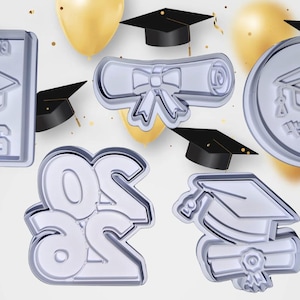 Könnte beinhalten: Eine Sammlung silberfarbener Ausstecher zum Thema Abschluss. Designs umfassen einen Mortarboard, ein Diplom und die Zahlen "2023". Der Hintergrund zeigt goldene Luftballons und kleine schwarze Mortarboards.