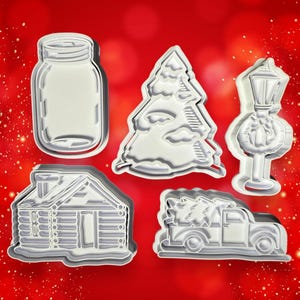 Peut inclure: Ensemble de cinq emporte-pièces de Noël en plastique blanc. Les emporte-pièces sont en forme de bocal en verre, d'arbre de Noël, de cabane, de camion avec un arbre de Noël dans la benne et de lampadaire avec une couronne.