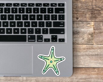 Puede incluir: Una pegatina de estrella de mar verde y amarilla con un diseño de mandala. La pegatina está en una computadora portátil plateada.