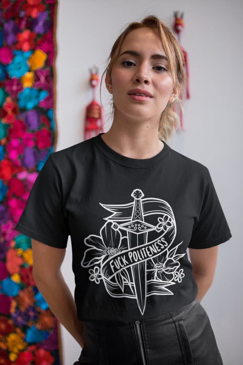 Op de afbeelding: Zwart T-shirt met een wit grafisch ontwerp van een dolk met bloemen en een banner met de tekst "F*CK POLITENESS".