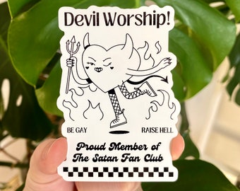 Puede incluir: Pegatina en blanco y negro con un diablo de dibujos animados en forma de corazón que sostiene un tenedor. El texto "Devil Worship!" está en la parte superior de la pegatina. El texto "Be Gay" y "Raise Hell" están en la parte inferior de la pegatina. El texto "Proud Member of The Satan Fan Club" está en el medio de la pegatina.