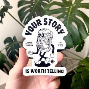May include: A white sticker with a black cartoon microphone character and the text "YOUR STORY IS WORTH TELLING". The sticker also includes the text "CANADIAN BROADCASTING CORPORATION" and "COAST TO COAST".