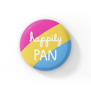 May include: A circular badge with a pink, yellow, and blue colour scheme, with the words "happily PAN" in white. The badge has a speckled texture and a glossy finish, with a simple, clean design.
