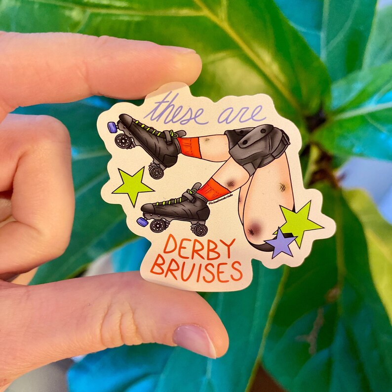 May include: A sticker featuring a cartoon illustration of legs wearing roller derby skates and knee pads. The legs are shown with bruises and wearing red socks. The text "these are" is above the legs, and "DERBY BRUISES" is below.
