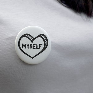 May include: White button with a black hand-drawn heart that says "MYSELF" inside.