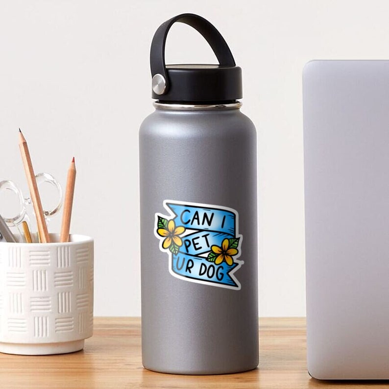 May include: A blue and white sticker with a banner that says "Can I Pet Ur Dog" with yellow flowers on either side.