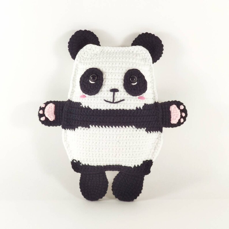 May include: A handmade crochet panda bear pillow in white and black. The panda has black button eyes, pink cheeks, and a smiling mouth. The panda's arms and feet have pink paw pads.