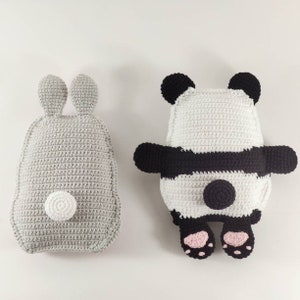 May include: Two handmade crochet pillows: a gray bunny-shaped pillow with a white pom-pom tail and a panda-shaped pillow in black, white, and pink. The panda pillow features black ears, arms, and feet, with a black stripe across its body.