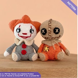 Peut inclure: Deux poupées au crochet faites à la main : un clown avec des cheveux orange et une poupée Sam avec une tête en sac de jute. La poupée clown a un visage blanc, un sourire rouge et une tenue grise. La poupée Sam est orange avec des yeux en croix noirs. Le texte "PATTERN" est inclus.