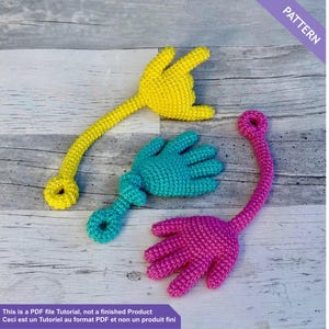 Könnte beinhalten: Drei gehäkelte handförmige Spielzeuge in Gelb, Türkis und Pink. Jedes hat einen langen, schlanken Stiel und eine Schlaufe am Ende. Das Bild enthält den Text "PATTERN" und einen Hinweis, dass es sich um ein PDF-Tutorial und nicht um ein fertiges Produkt handelt.