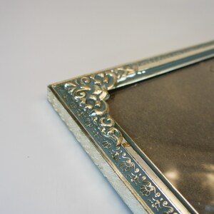 May include: A silver picture frame with a blue and gold ornate design. The frame is empty and ready for a photo.