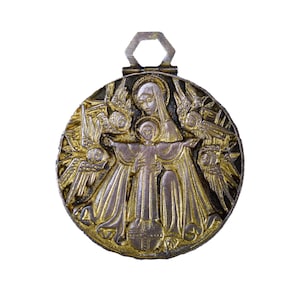 May include: A gold and silver toned metal pendant featuring a depiction of the Virgin Mary holding a baby Jesus. The pendant is surrounded by angels with wings and is attached to a hexagonal loop.