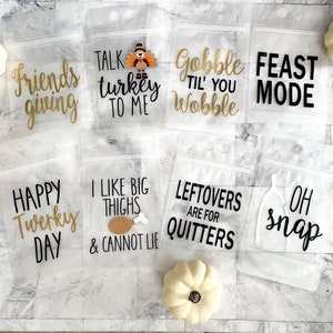 May include: Nine clear plastic bags with zipper closures, each decorated with a Thanksgiving-themed design and text. The text includes phrases like "Friends giving", "Talk turkey to me", "Gobble til you wobble", "Feast mode", "Happy Twerky Day", "I like big thighs & cannot lie", "Leftovers are for quitters", and "Oh snap".